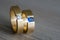 Closeup of couple golden wedding rings with diamond and sapphire on a wooden table