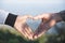 Closeup of couple making heart shape with hands, Couple in love, Focus on hands, Man and woman tourists in the mountains at sunset