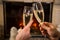 Closeup of couple`s hands with glass of champagne near fireplace