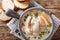 Closeup of creamy fish soup with cod, salmon, carrot and celery in a bowl served with fresh bread. horizontal top view