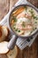 Closeup of creamy fish soup with cod, salmon, carrot and celery in a bowl served with fresh bread. Vertical top view