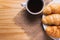 Closeup croissant with coffee on wooden table. breakfast concept