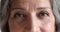 Closeup cropped face view of older woman looking at camera