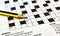 Closeup of crossword puzzle from a newspaper with a black and yellow lead pencil