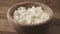 Closeup crumbly cottage cheese in wood bowl