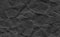 Closeup crumpled dark grey or black paper texture background.Dark ,black paper sheet board with space for text ,pattern or abstrac