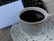 Closeup of a cup of black coffee with blank white notepaper and part of old typewriter keyboard. Copy space for business text.