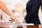 Closeup customer guest hand reaching for traditional reception bell with uniformed employee in background