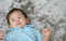 Closeup cute asian kid lied on floor in happy emotion with smile face on gray carpet textured background