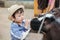 Closeup cute asian kid milking calf by bottle of milk in farm background