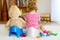 Closeup of cute little 12 months old toddler baby girl child sitting on potty. Kid playing with big plush soft toy