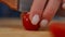 Closeup cutting red ripe tomato on two halves. Close-up female Caucasian hands slicing tasty healthful vegetable on