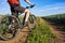 Closeup of cyclist man legs with mountain bike on outdoor trail in the summer field.