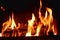 Closeup of dancing flames of burning wooden logs in fireplace with black background warming light in Christmas holidays.