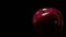 Closeup of a dark red shiny apple on a black background