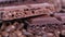 Closeup of dark roasted coffee beans and chocolate on rotating table. Aromatic coffee grains and sweet choco pieces turning.