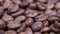 Closeup of dark roasted coffee beans on rotating table. Aromatic coffee grains turning.