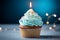 Closeup delicious birthday cupcake with burning candle on blue