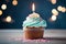 Closeup delicious birthday cupcake with burning candle on blue