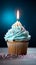 Closeup delicious birthday cupcake with burning candle on blue