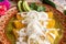 Closeup of delicious Mexican green enchiladas with sour cream and cheese, in a red patterned bowl