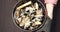 Closeup of delicious mussels with truffle sauce and herbs in a plate. Female hands in gloves spinning a bowl of seafood.