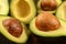 Closeup detail - heap of avocados cut in half, with brown seeds