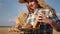 Closeup details of a young handsome lady farmer with a hat holding a box full of bread in the middle of a large golden