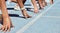 Closeup of determined group of athletes in starting position line to begin sprint or run race on sports track stadium