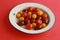 Closeup of different cherry tomatoes in a bowl on a red surface