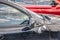 Closeup of dirty car with right side mirror taped on and scratches to it and window - lots of reflections of blue sky and a bright