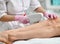 Closeup. Doctor-cosmetician performs a cosmetic procedure on the patient`s legs with electronic medical equipment in beauty parlor