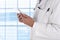 Closeup of a doctor with a table computer in front of a large window in a modern medical facility. Man is unrecognizable