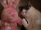 Closeup of a domestic cat on the sofa with a pink stuffed rabbit toy under the lights