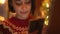 closeup dreamy smiling woman in cute red festive sweater on background of lights using phone, texting, messaging