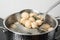 Closeup of dumplings on skimmer over stewpan with boiling water