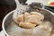 Closeup of dumplings on skimmer over stewpan with boiling water.