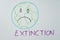 Closeup of the Earth drawn on a whiteboard with a sad face, and the word "extinction" at the bottom