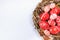 Closeup Easter red eggs with folk white pattern inside bird nest on white. Top view