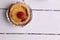 Closeup of an egg tart with a raspberry on top on a white rustic background