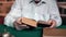 Closeup elderly male hands taking antique book reading at desk in library