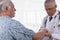 Closeup of a elderly male patient wearing a hospital gown as a doctor examines his right arm. Focus is on the patient