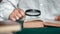 Closeup elderly wrinkled male hands reading antique paper book use magnifying glass at table home