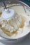 Closeup of electric mixer with whipped smooth cream for cake. Batter being whipped. Mixing white dough in bowl with motor mixer.