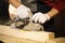 Closeup of electric plane throws sawdust while woodworker making wooden detail