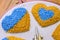Closeup of embroidery project - hearts in Ukrainian flag colors, and part view of two punch needles