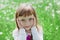 Closeup emotional portrait of cute little girl with beautiful soulful eyes standing on a green meadow