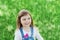 Closeup emotional portrait of cute little girl with smile standing on a green meadow