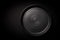 Closeup empty round black ceramic plate with pattern of circles on dark background with copy space. Concept modern