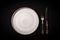 Closeup empty round gray ceramic plate on black background, vintage cupronickel fork, knife with copy space. Concept